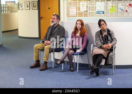 Tre persone sedute su sedie in una sala d'attesa di uno studio medico Foto Stock