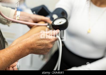 Infermiera che prende la pressione sanguigna di un paziente Foto Stock