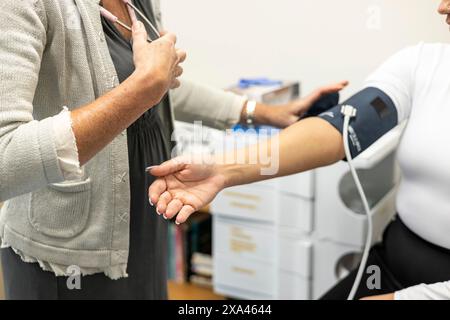 Infermiera che prende la pressione sanguigna di un paziente Foto Stock