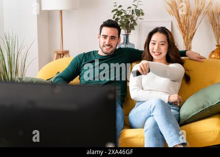 Una coppia che si rilassa su un divano giallo a casa Foto Stock