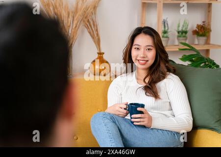 Donna sorridente sul divano che regge una tazza Foto Stock
