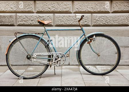 Vecchia bicicletta parcheggiata accanto al muro di pietra Foto Stock