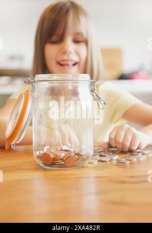 Sorridente Ragazza mettendo le monete in vaso Foto Stock