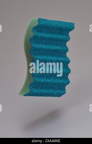Spugna blu ondulata che galleggia a mezz'aria su sfondo grigio Foto Stock
