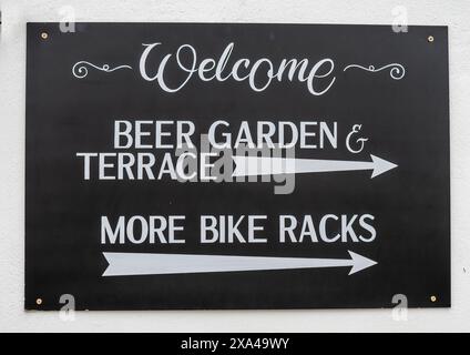 Cartello decorativo del pub sulla parete che mostra la direzione del giardino della birra, della terrazza e dei portabiciclette. Foto Stock