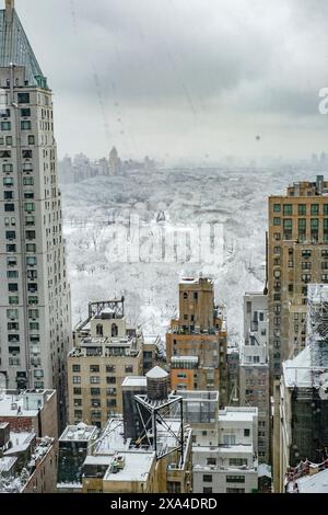 Un paesaggio urbano innevato presenta un parco ricoperto di bianco, circondato da alti edifici, con cieli sovrastati. Foto Stock