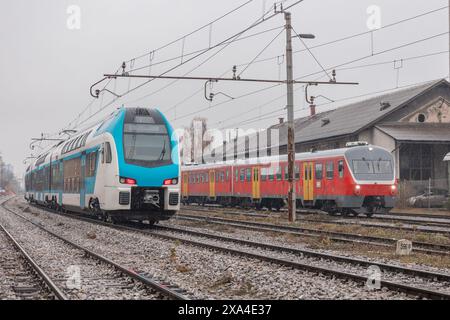 Vecchi e nuovi treni passeggeri su binari adiacenti. Vecchia strada per nuovi trasporti ferroviari. Foto Stock