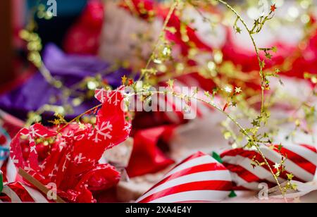 Un vivace e festoso primo piano di carta e decorazioni natalizie con strisce rosse e bianche, motivi a fiocco di neve e ghirlande stellate dorate. Foto Stock
