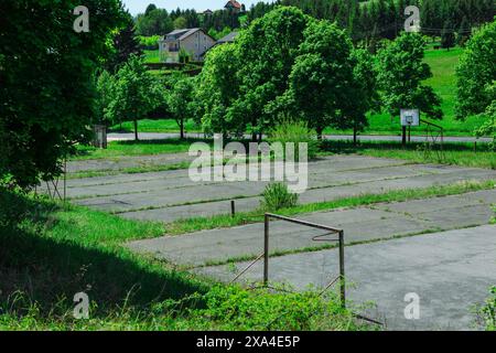 Campo di basket della scuola politica ormai deserta a kumrovec, croazia. Vecchio maestoso edificio che decadde nel tempo, un tempo glorioso ora dimenticato. Rovine di Foto Stock