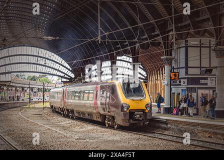 Un treno moderno si trova in una storica piattaforma della stazione ferroviaria sotto una tettoia di ferro del XIX secolo. Alcuni passeggeri si trovano vicino a una colonna. Foto Stock