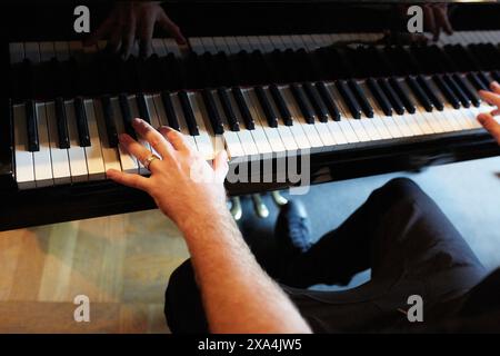 Pionista maschile seduto ad un classico pianoforte nero che suona Foto Stock