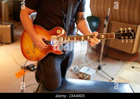 Un chitarrista suona una chitarra elettrica Sunburst Gibson Les Paul in uno studio di registrazione, con particolare attenzione alle mani e allo strumento sulla tastiera. Foto Stock