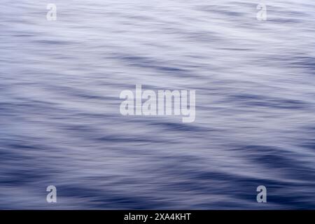 Si tratta di un'immagine tranquilla che mostra la superficie liscia e fluente dell'acqua in sfumature di blu, catturando il delicato movimento delle onde. Foto Stock