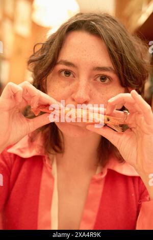 Donna con camicetta rosa che tiene un gambero a un tavolo da pranzo. Foto Stock