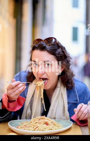 Donna che si gode un piatto di spaghetti in un ambiente all'aperto Foto Stock