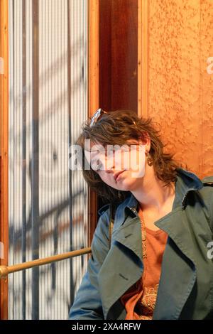 Giovane donna casual con occhiali da sole sulla testa appoggiata su un corrimano in interni Foto Stock