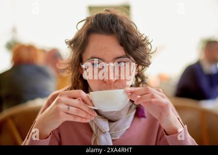 Giovane donna che si gode una tazza di caffè in un accogliente ambiente da caffe'. Foto Stock