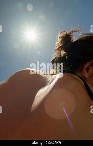 Vista posteriore di una persona con luce solare che splende sulle spalle, creando un effetto flare dell'obiettivo. Foto Stock