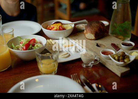 Una colazione continentale fresca con una varietà di piatti tra cui pane, insalata, frutta e bevande su un tavolo di legno. Foto Stock