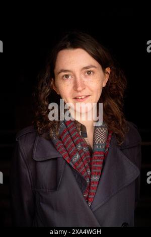 Donna sorridente con un cappotto in piedi su uno sfondo scuro. Foto Stock