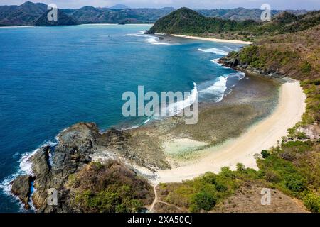 Vista aerea di una piccola spiaggia tropicale vuota circondata dall'oceano blu (Semeti Beach, Lombok) Foto Stock