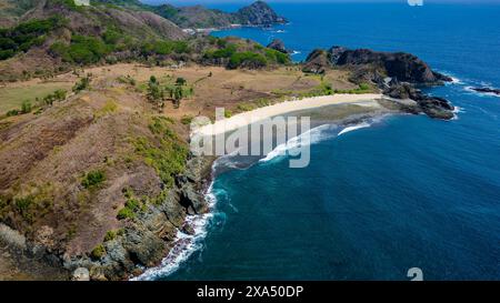 Vista aerea di una piccola spiaggia tropicale vuota circondata dall'oceano blu (Semeti Beach, Lombok) Foto Stock