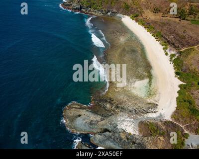 Vista aerea di una piccola spiaggia tropicale vuota circondata dall'oceano blu (Semeti Beach, Lombok) Foto Stock