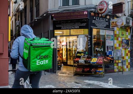 Siviglia, Spagna. 4 febbraio 2024 - Uber Eats consegna ciclista sulle strade storiche della città vecchia di Siviglia Foto Stock