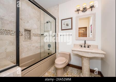 Bagno con pareti bianche, pavimento in piastrelle beige, vasca e lavandino Foto Stock