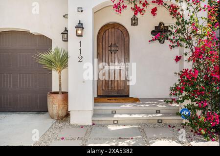 Casa con porta marrone e vivaci fiori rossi sui gradini Foto Stock