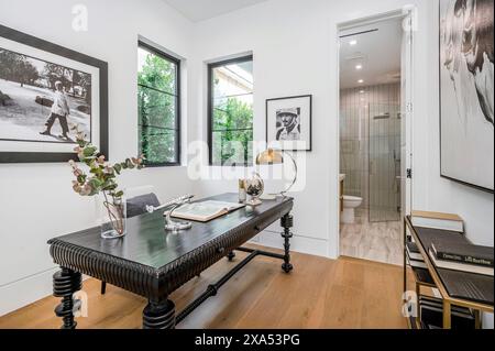Ufficio domestico bianco con mobili neri e pavimento in legno Foto Stock