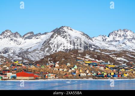 Groenlandia sudorientale, regione di Ammassalik. Tipiche case colorate nella remota comunità di Tasiilaq. Vista panoramica sul ghiaccio in primavera. Solo editoriale. Foto Stock