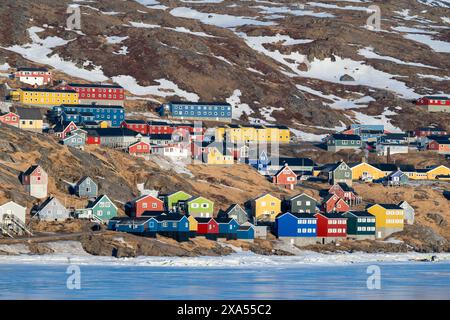 Groenlandia sudorientale, regione di Ammassalik. Tipiche case colorate nella remota comunità di Tasiilaq. Vista panoramica sul ghiaccio in primavera. Solo editoriale. Foto Stock