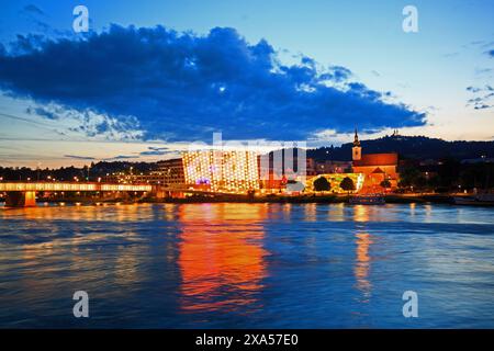 Vienna sul Danubio con edifici illuminati che si riflettono nell'acqua Foto Stock