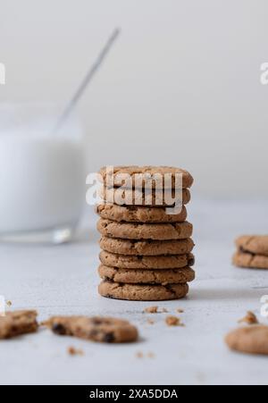 Una verticale di biscotti al cioccolato su una pila con un bicchiere di latte Foto Stock