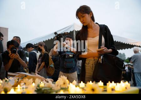 Taipei, Taiwan. 4 giugno 2024. Una donna osserva fiori e candele senza fiamma su un tavolo con le lettere 8964 per ricordare la data del massacro di piazza Tienanmen del 1989, il 4 giugno, in occasione di una veglia commemorativa del 35° anniversario della repressione, nota anche come incidente del 4 giugno, al Chiang Kai-shek Memorial Hall di Taipei, Taiwan. In quel giorno, l'esercito cinese uccise molti manifestanti in piazza Tienanmen e nei dintorni di Pechino che chiedevano una riforma democratica nel 1989. Foto Stock