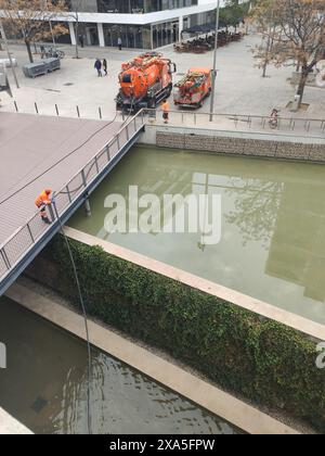 Un operatore che raccoglie l'acqua dal laghetto urbano con un tubo flessibile per riempire il dumper Foto Stock