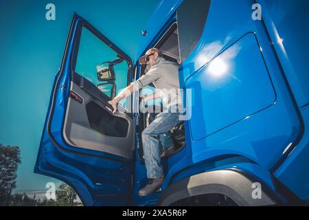Il conducente di camion maschio caucasico scende dal veicolo alla fermata Foto Stock