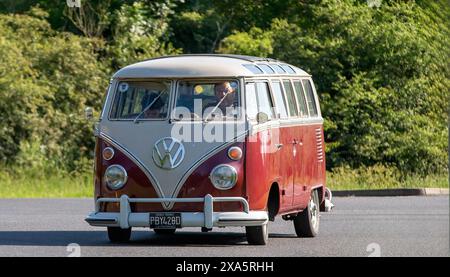 Stony Stratford, Regno Unito - 2 giugno 2024: 1966 Volkswagen camper Van rosso che guida su una strada di campagna britannica Foto Stock