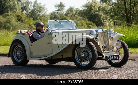 Stony Stratford, Regno Unito - 2 giugno 2024: 1947 crema MG Midget classica auto sportiva britannica che guida su una strada di campagna britannica Foto Stock