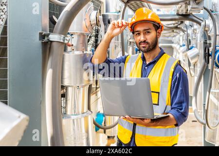 Un uomo che usa un laptop in un impianto di produzione per lavorare a un progetto in Tailandia, Bangkok Foto Stock