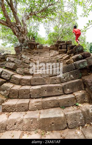 Bambini che salgono i gradini per le rovine superiori, Wat Pho (o Wat Phu), sito patrimonio dell'umanità dell'UNESCO, Champasak, Laos Foto Stock