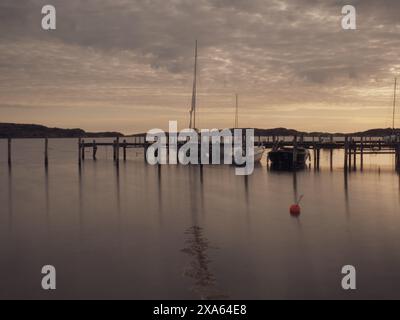 Diverse piccole imbarcazioni ormeggiate dal molo in acqua Foto Stock