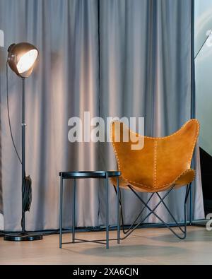 Una sedia in pelle posizionata vicino a un tavolo accanto a una lampada Foto Stock