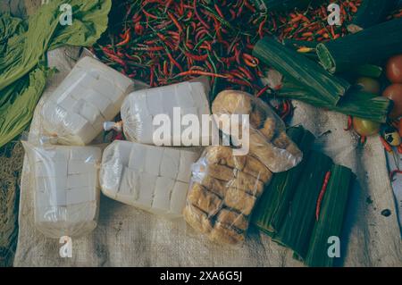 Vista dall'alto della cagliata di soia, del tofu fresco o del tahu e del tempeh o della soia fermentata avvolta in foglia di banana venduta nel mercato locale di Berastagi, Indonesia Foto Stock