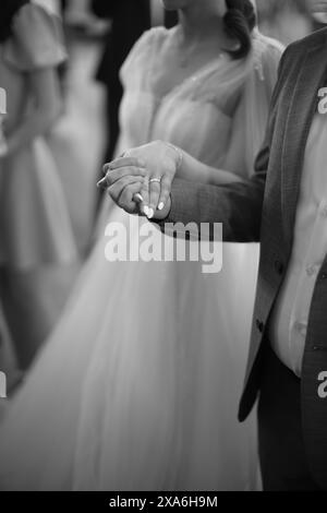Gli sposi in abito formale camminano mano nella mano lungo il corridoio. Foto Stock