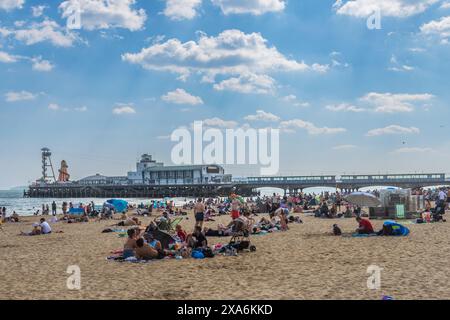 East Cliff Beach, Bournemouth, Regno Unito - 2 giugno 2024: Bagni di sole di fronte al molo di Bournemouth. Foto Stock