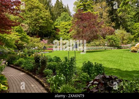 . Percorso attraverso alberi colorati e aiuole di fiori nel giardino sommerso, Butchart Gardens, Victoria, British Columbia. Foto Stock