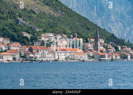 Pittoresca cittadina di Perast annidata lungo le rive della Baia di Cattaro, circondata da splendide montagne, Montenegro Foto Stock