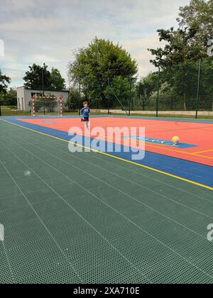 Un bambino che gioca su un campo da basket all'aperto Foto Stock